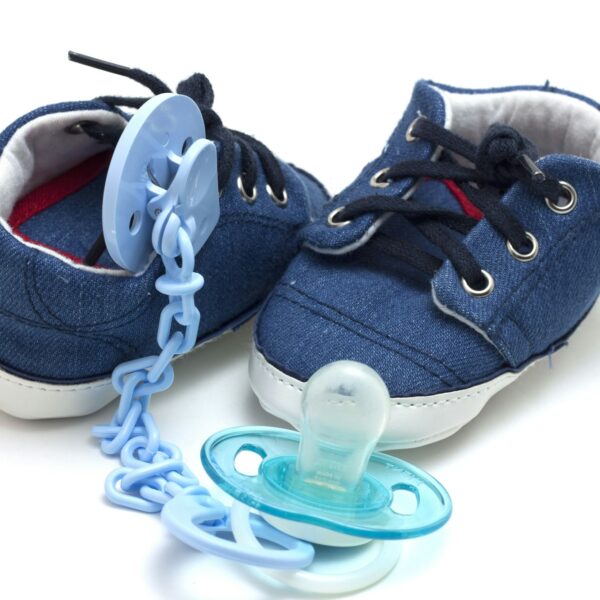 Blue baby shoes with a coordinating pacifier hung from a metal chain on the front